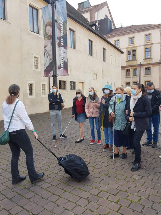 Le groupe suit la guide qui trimballe dans sa valise les précieux outils utiles à la visite.